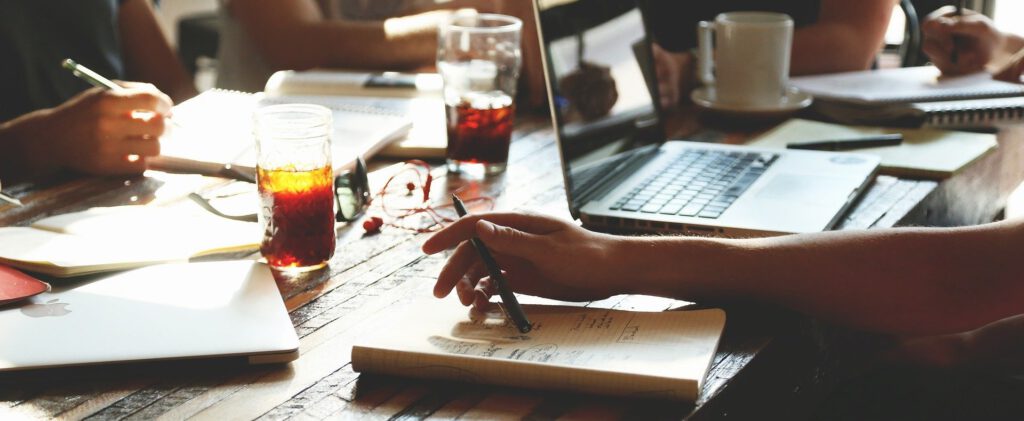 Auf einem Tisch mit Block und Laptop wird eine Instagram Strategie für Unternehmen ausgearbeitet